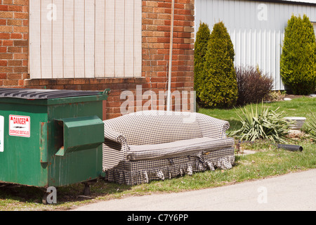 Alte couch außerhalb neben einem Mülleimer Mülltonne Stockfoto