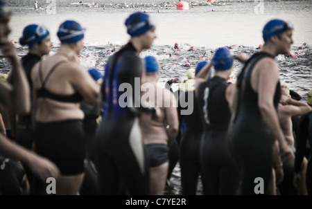 Aus Fokus Schwimmer Inszenierung für den Start einen Triathlon ist zuvor gestartete Welle der Schwimmer im Fokus im Hintergrund. Stockfoto