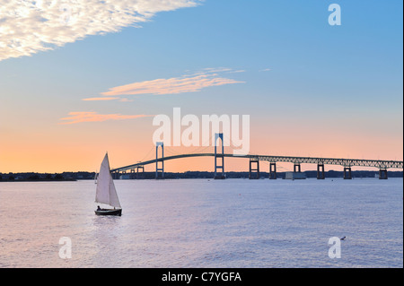 Claiborne Pell Newport Bridge und Segelboot. Sonnenuntergangshimmel mit kontrastierenden Farben von Pastellorange und Blau, Newport, Rhode Island, USA Tourismus Stockfoto