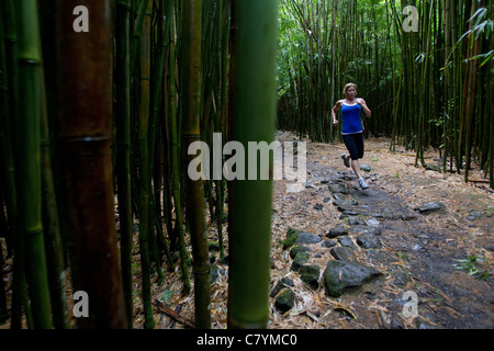 Frau läuft in einem tropischen Bambuswald auf Maui Stockfoto