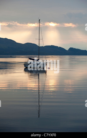 Eine Yacht ankern in Loch Lomond, Schottland als die Sonne aufgeht. Stockfoto