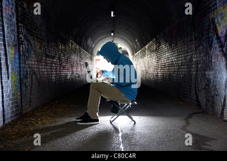 Computer-Benutzer, Hacker, verschwörerisch, in einem Tunnel mit einem Laptop sitzt. Symbolbild, Computer-Internet-Kriminalität. Stockfoto