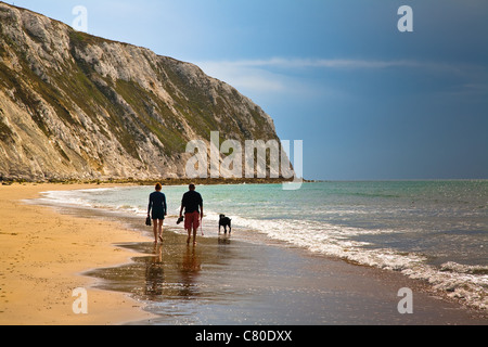 Ein paar, die ihren Hund an einem Sandstrand bei Ebbe, Sandown auf der Isle Of Wight, England Stockfoto