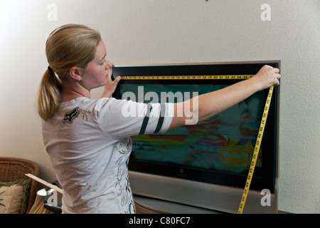 Teenager-Mädchen misst die Maße von einem 32-Zoll-TV-Bildschirm. Herr © Myrleen Pearson Stockfoto