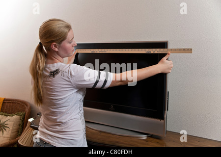 Teenager-Mädchen misst die Maße von einem 32-Zoll-TV-Bildschirm. Herr © Myrleen Pearson Stockfoto