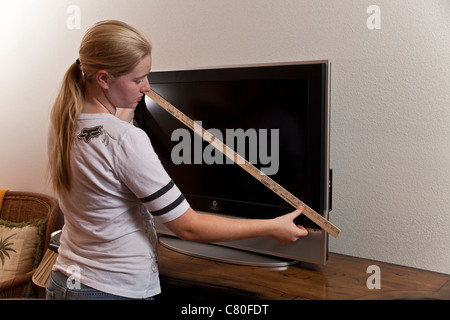 Teenager-Mädchen misst die Maße von einem 32-Zoll-TV-Bildschirm. Herr © Myrleen Pearson Stockfoto