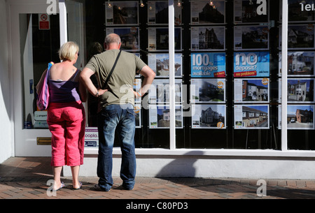 Paar sucht die Eigenschaft für Verkauf-Boards in einem Makler-Fenster Stockfoto