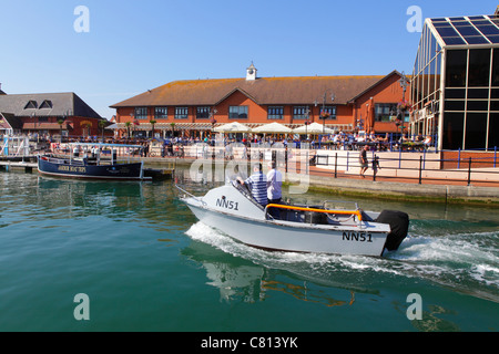 Boot vorbei an Cafés am Ufer des Lower Quayside, Sovereign Harbour, Eastbourne, East Sussex, England UK GB Stockfoto