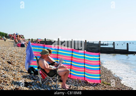 Pärchen entspannen sich während eines indischen Sommers im Oktober am Strand von West Wittering in der Nähe von Chichester, West Sussex, England, Großbritannien Stockfoto