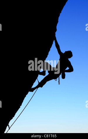 Silhouette der Kletterer Klettern einer überhängenden Felswand mit blauem Himmelshintergrund Stockfoto