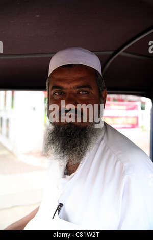 Porträt von bärtigen muslimischen Mann - eine Autorikscha-Fahrer - mit traditionellen gewebten Mütze; Innenraum der Kabine Stockfoto