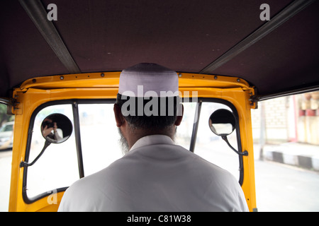 Ansicht der Rückseite Autorikscha-Fahrer, ein muslimischer Mann mit traditionellen gewebten Mütze, Beifahrersitz entnommen Stockfoto