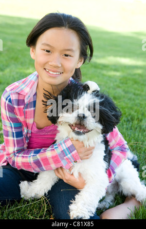 Chinesisches Mädchen sitzen im Rasen mit Shih Tzu Hund Stockfoto