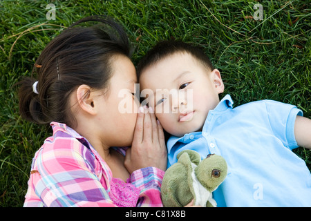 Chinesisches Mädchen Verlegung in Rasen und Flüstern, Bruder Stockfoto