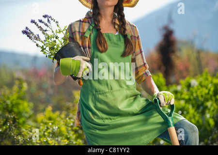 Kaukasische Frau mit Schaufel und Blumen in Gärtnerei Stockfoto