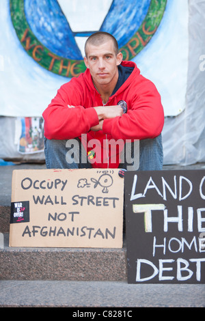 Ein Mann sitzt hinter Protest Zeichen "Occupy Wall Street, nicht Afghanistan" Förderung während der Demonstration Occupy Wall Street Stockfoto