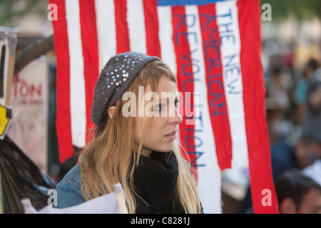 Ein Demonstrant vor einer amerikanischen Flagge mit den Worten "Die neue amerikanische Revolution" während Demonstration Occupy Wall Street Stockfoto