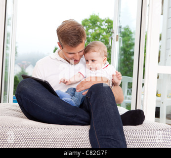 Vater und Sohn sitzen vor Fenster mit einem digitalen tablet Stockfoto