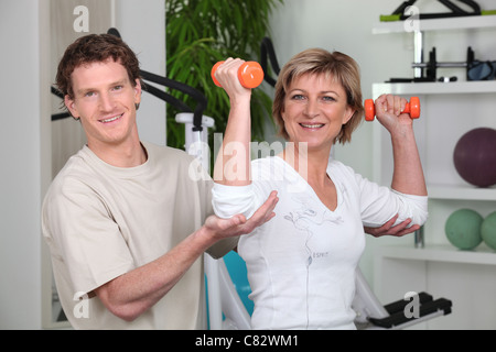 Frau von ihrem persönlichen Trainer geholfen Stockfoto