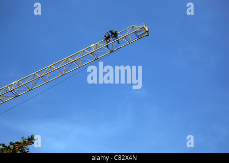 hoch oben in der Luft zwei Feuerwehrmänner Klettern eine Feuerwehr Drehleiter Stockfoto