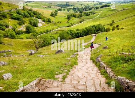 Wanderer, die ihren Weg nach unten den Weg bis zu dem Kalkstein Pflaster über Malham Cove in den Yorkshire Dales, England Stockfoto