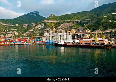 Ein Handelsschiff, geladen mit Ladung im Hafen von Rom, flankiert von den grünen Bergen im Hintergrund, Civitavecchia, Italien Stockfoto