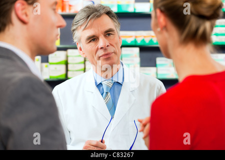 Apotheker berät Kunden - ein Mann und eine Frau - in seiner Apotheke Stockfoto