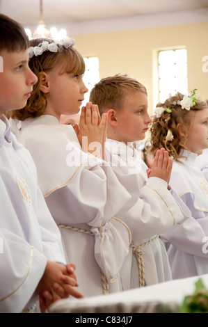 Kinder akzeptieren die erste Heilige Kommunion Stockfoto