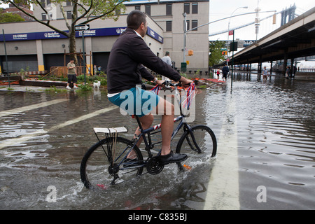 Biker auf der überfluteten Straße unter Manhattan Bridge, New York, während Hurrikan Irene. New York City, USA Stockfoto