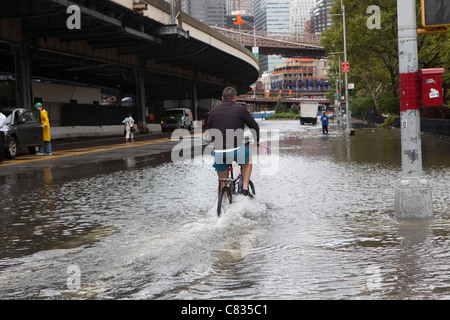 Biker auf der überfluteten Straße unter Manhattan Bridge, New York, während Hurrikan Irene. New York City, USA Stockfoto