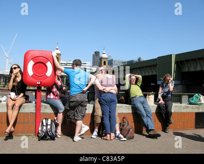 Menschen sitzen auf der Mauer von der Themse London UK Stockfoto