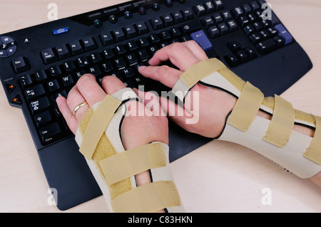 Mann mit Karpaltunnelsyndrom und tragen Handgelenksschienen mit einer Computertastatur Stockfoto