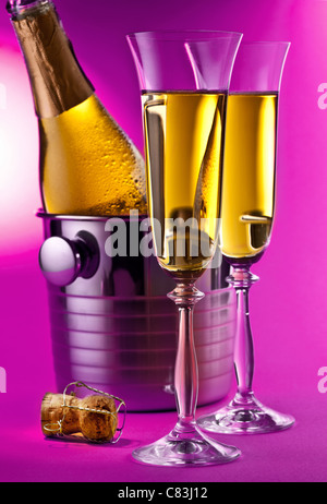 Flasche Champagner im Kühler und zwei Sektgläsern. Isoliert auf einem rosa Hintergrund. Stockfoto