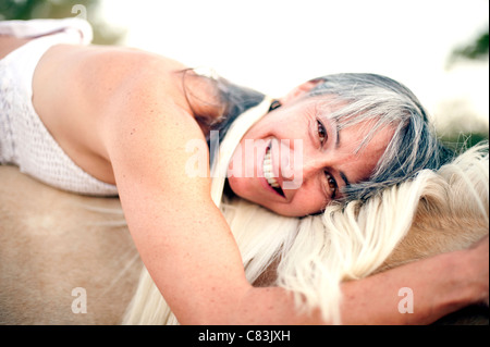 Porträt einer Frau legen den Kopf auf dem Hals der Pferde hautnah. Stockfoto