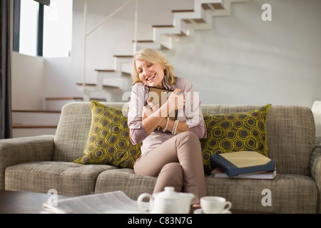 Frau umarmt gerahmtes Foto auf couch Stockfoto