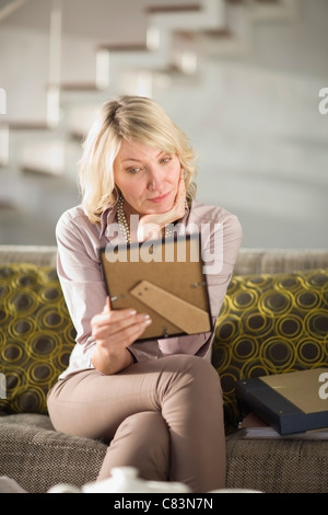 Frau bewundern gerahmtes Foto auf couch Stockfoto