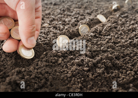 Mann, die Anpflanzung von Euro-Münzen im Boden Stockfoto