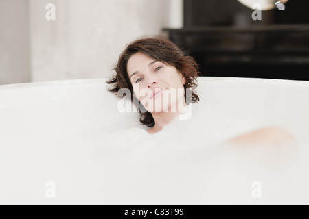 Lächelnde Frau unter Schaumbad Stockfoto