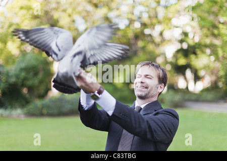 Geschäftsmann füttern Tauben im park Stockfoto