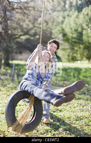 Mann schob Freundin auf Reifenschaukel Stockfoto