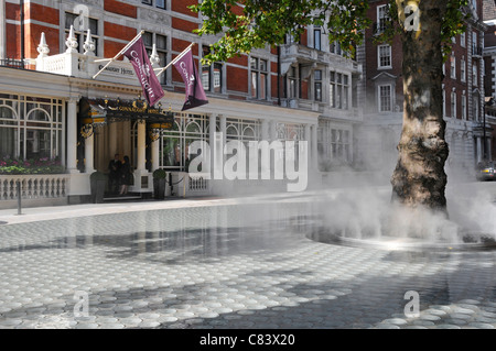 Street Scene Dampf Nebel Dampfwolke auf "Stille" Wasserspiel stieg von Baumstamm Carlos Place Mayfair Connaught Hotel Beyond London West End UK Stockfoto