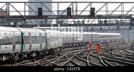 Gruppe von Eisenbahnarbeitern auf elektrifiziertem Gleis, die gut sichtbare Kleidung tragen Züge, die vom Bahnhof London Bridge in England ankommen Stockfoto