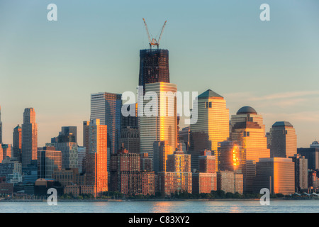 Der Sonnenuntergang Himmel gefärbt wird von Gebäuden in lower Manhattan, einschließlich der World Financial Center und Battery Park City reflektiert. Stockfoto