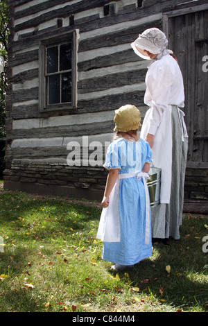 Mutter und Mädchen gehen mit ein Melken blass von einem Blockhaus Stockfoto