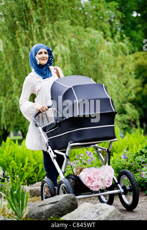 Frau im Kopftuch Kinderwagen schieben Stockfoto