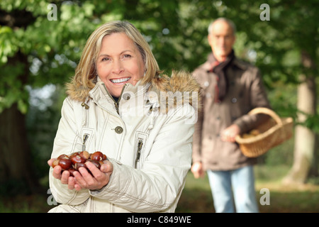 Reife Frau in Wäldern mit Mann mit Kastanien Stockfoto