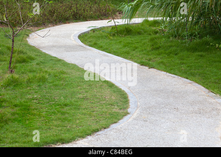 Rasen, Reed, kleiner Baum und geschwungenen Gehweg rund um Rasen. Stockfoto