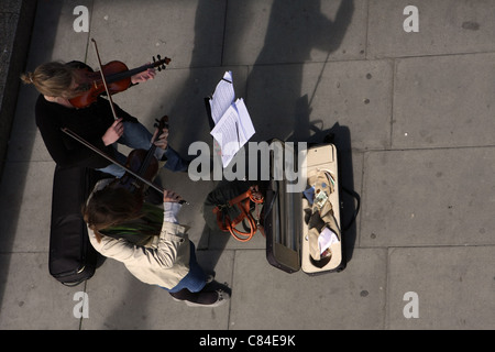 Blick hinunter auf zwei junge Frauen, die Violinen um Geld zu spielen, am Ufer der Themse, London Stockfoto