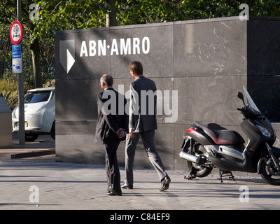 Logo mit zwei Männern zu Fuß vorbei an ABN Amro Bank Hauptsitz in Amsterdam, Niederlande. Stockfoto