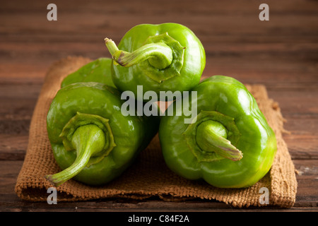 Drei grüne Paprika auf Jute und Holz Stockfoto